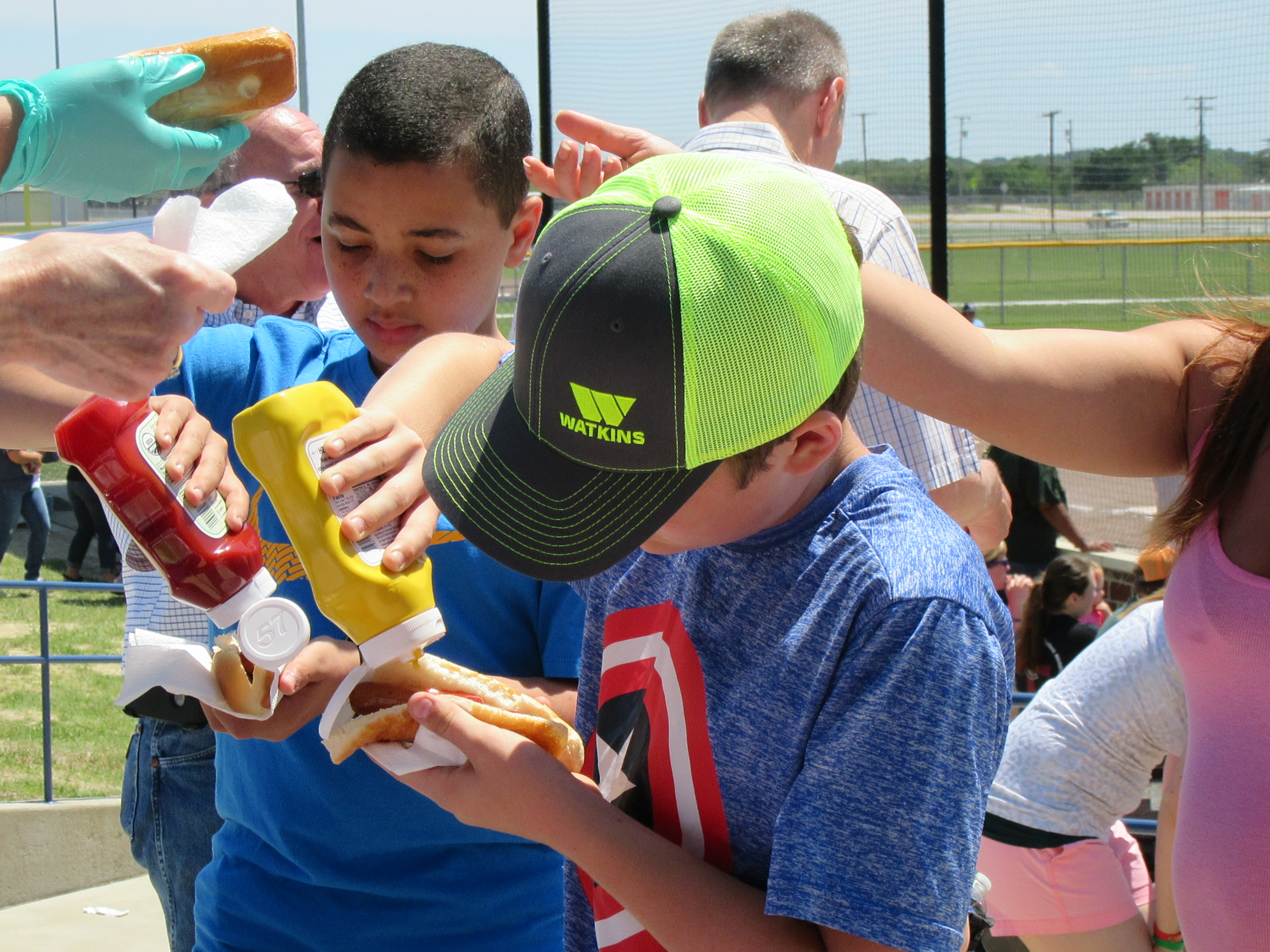 Kids putting ketchup and mustard on hotdogs
