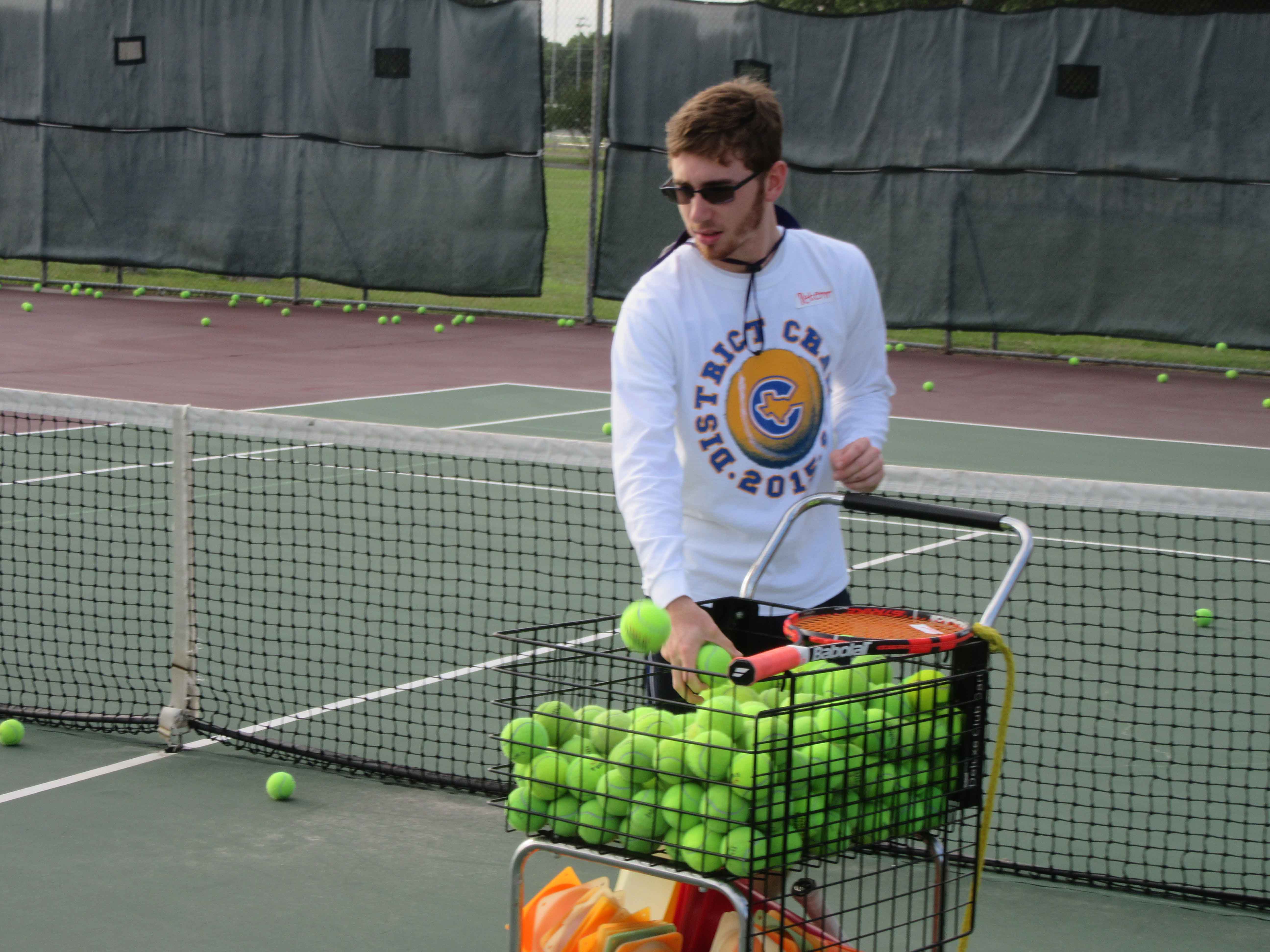 Man with cart of tennis balls